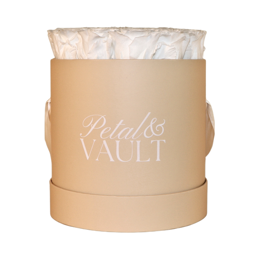 beige round hat box with white preserved roses on white background