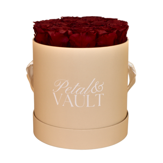 Beige cylindrical hat box with red roses and 'Petal & Vault' branding on a white background