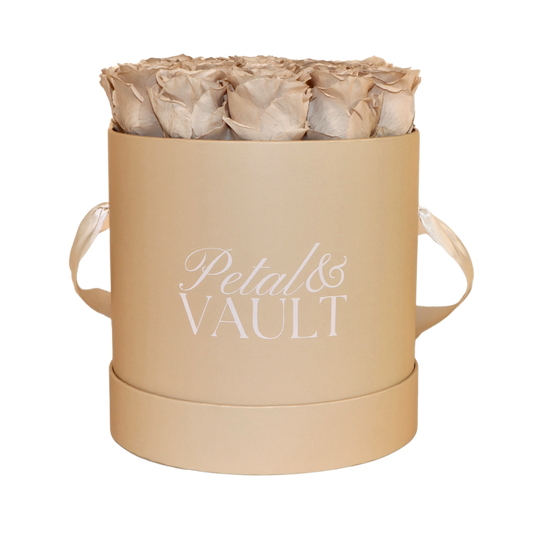Beige cylindrical hat box with 'Petal & Vault' branding containing beige roses on a white background