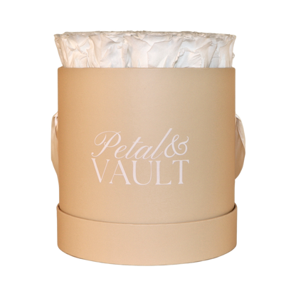 beige round hat box with white preserved roses on white background