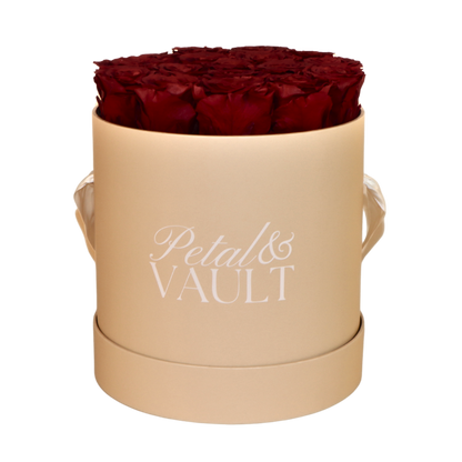 Beige cylindrical hat box with red roses and 'Petal & Vault' branding on a white background