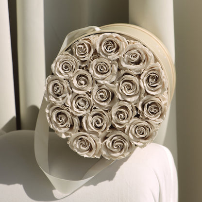 Round box filled with beige roses on a light background